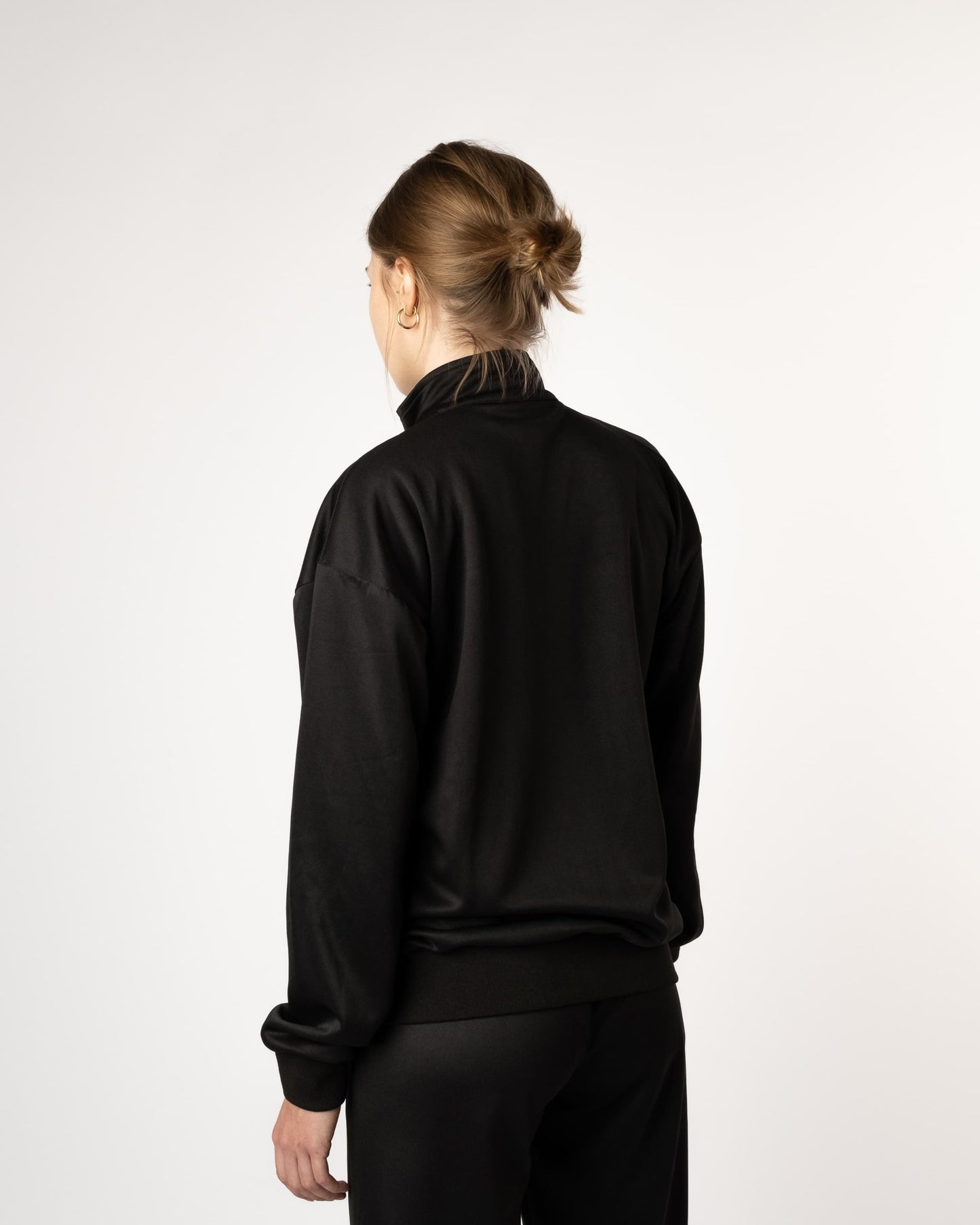 Achteraanzicht van vrouwelijke model in GJA Classic Track Jacket, eigentijdse en robuuste sportjas voor jonge vrouwen die zichzelf durven te onderscheiden in Nederland - Dames sport jas