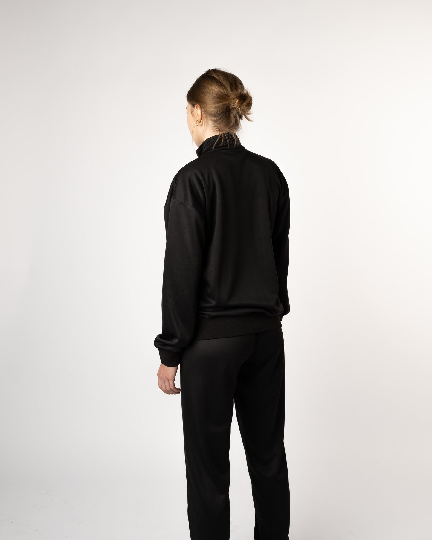 Achteraanzicht van model in GJA trainingspak, stoere en comfortabele trainingsbroek voor jonge dames - Gym Junkie Sportswinkel