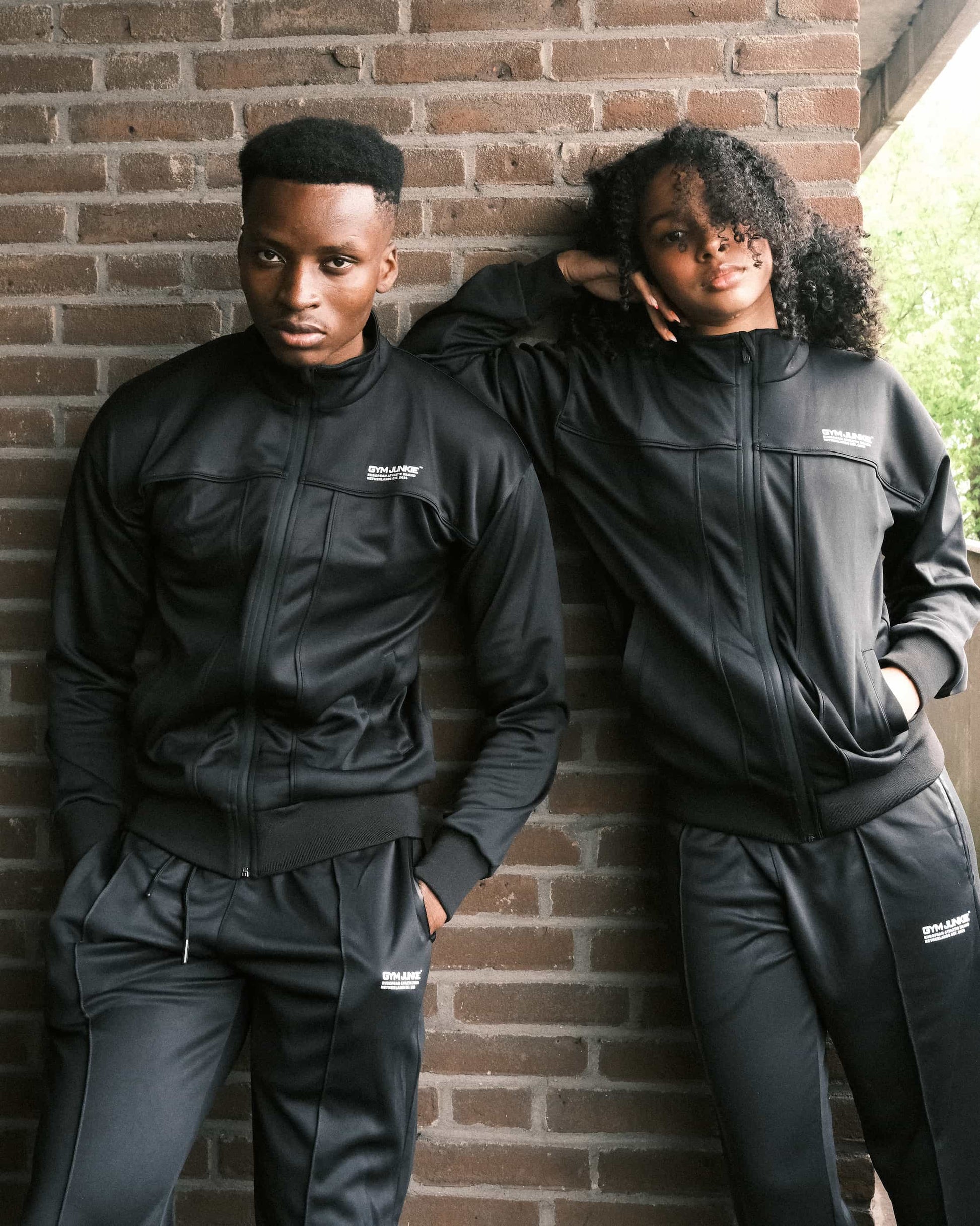 Man en vrouw in Gym Junkie trainingspakken, duo sportset voor jonge volwassenen in Nederland, uniseks stijl met comfortabele fit - Gym Junkie sportkleding