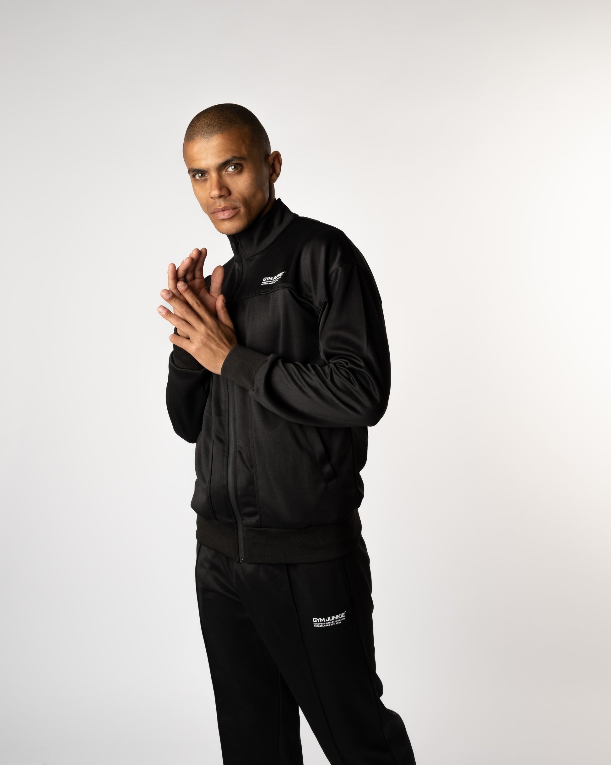 Vooraanzicht van model in Gym Junkie trainingsbroek en trainingjas voor heren, sportieve outfit voor mannen van 16–30 jaar in Nederland. - Gym Junkie Sportkelding voor mannen