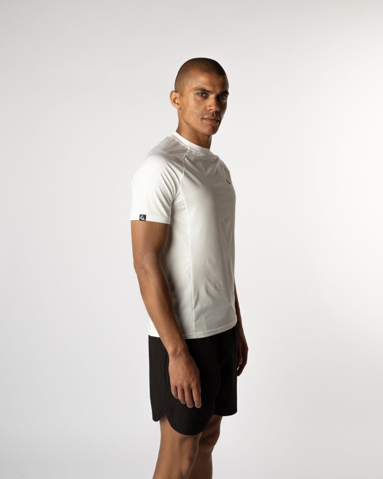 Detailfoto van de witte Gym Junkie Magna Trainings T-shirt met zichtbaar label op de mouw, premium activewear voor mannen - Heren Gym t-shirts