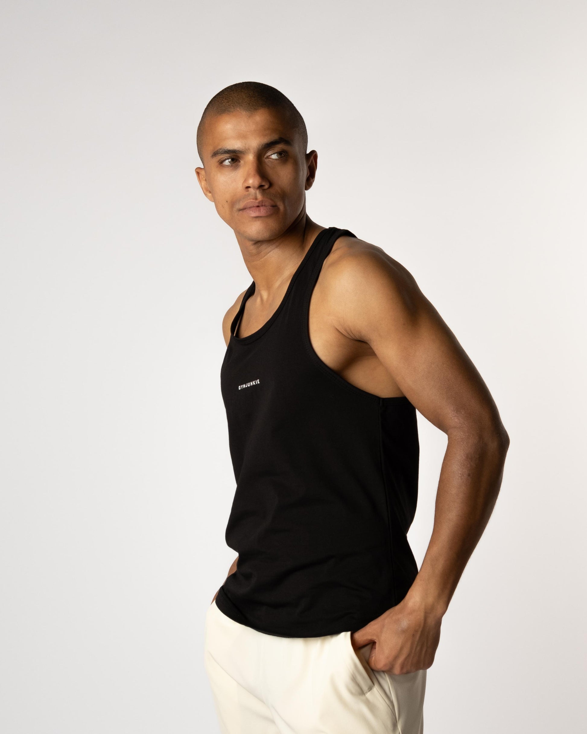 Zijaanzicht van een mannelijk model in Magna Stringer, met hand in de zak van Magna Sand shorts – Gym Junkie sportwinkel