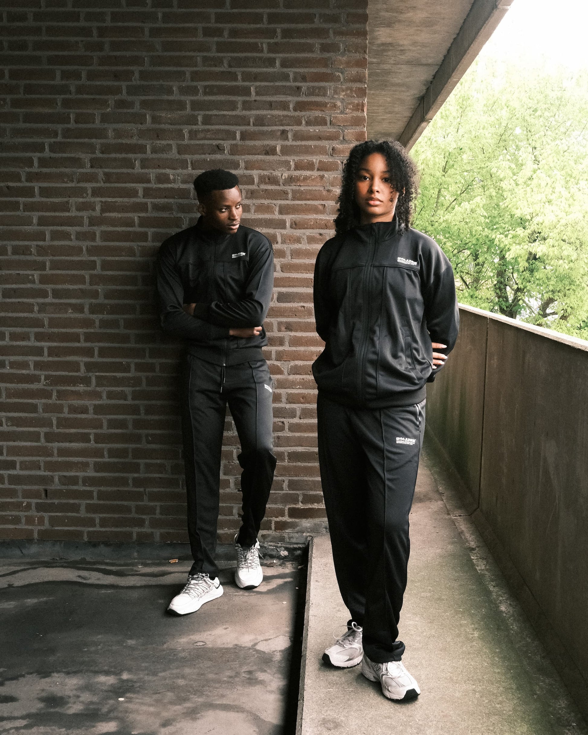 Man en vrouw dragen GJA trainingspak buiten, stijlvolle en krachtige sportoutfits voor jonge, gedurfde sporters die actief leven in Nederland
