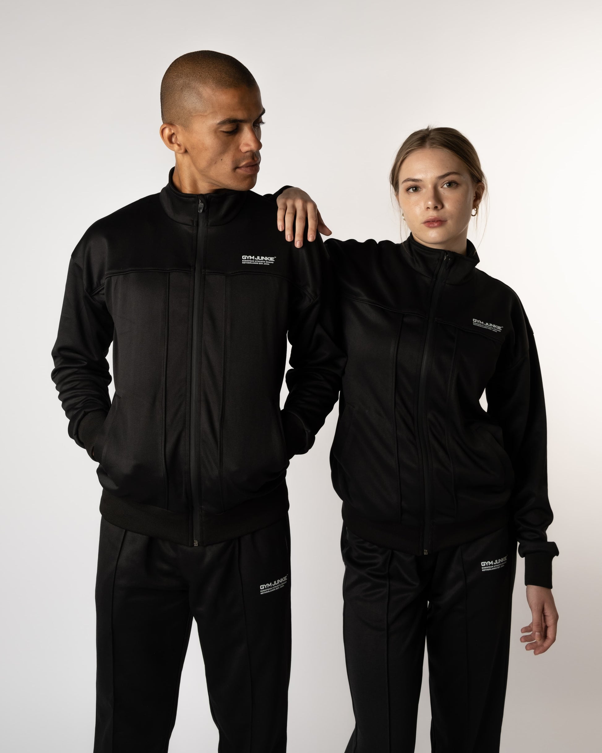 Man en vrouw dragen GJA trainingspakken tijdens actieve pose, krachtige en modieuze sportoutfits voor jonge, zelfverzekerde sporters die grenzen verleggen