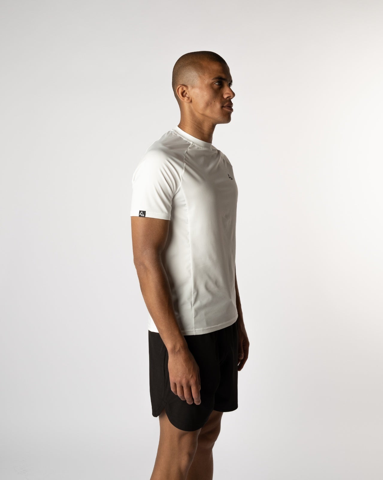 Zijaanzicht van een model in een witte sportshirt en zwarte Magna shorts, ontworpen voor performance en stijl - Gym t-shirts voor mannen