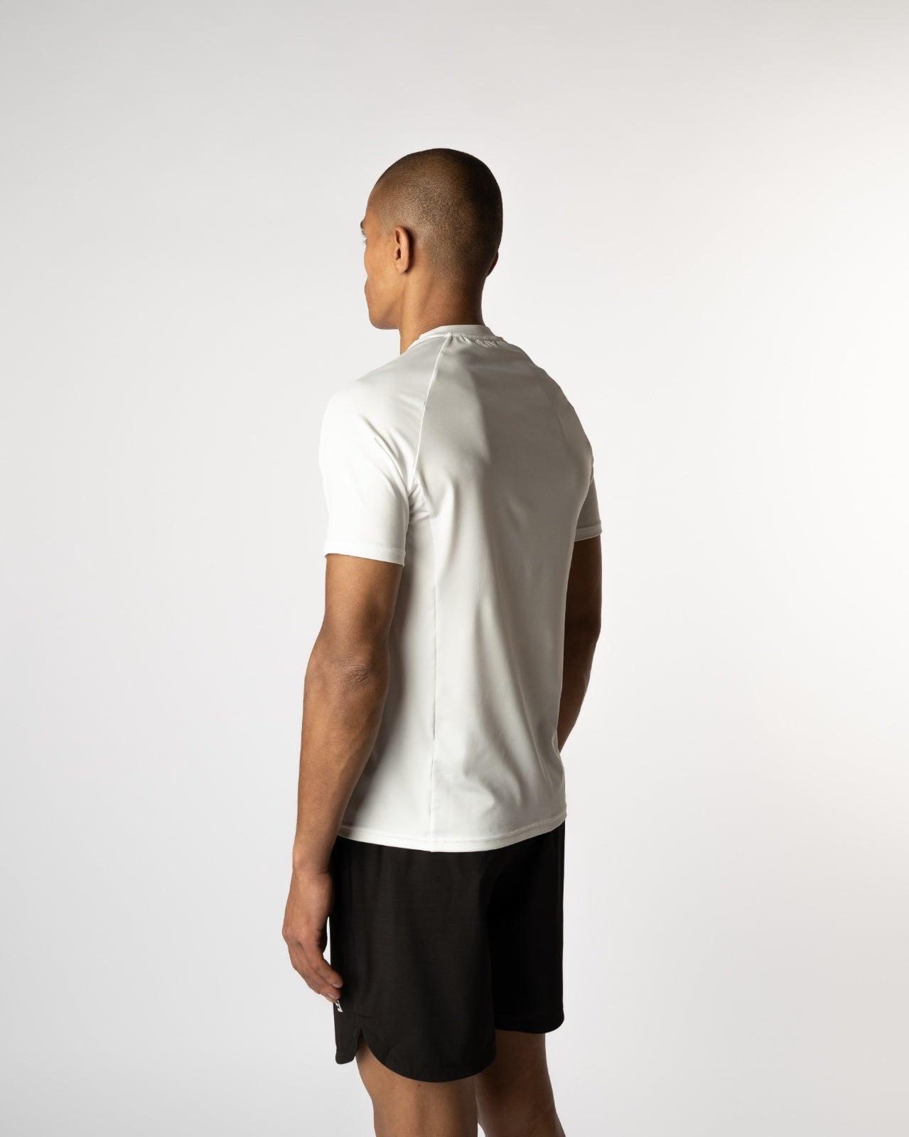 Achteraanzicht van een mannelijke model in de witte Magna Trainings Tee van Gym Junkie, sportief en clean design voor de moderne man