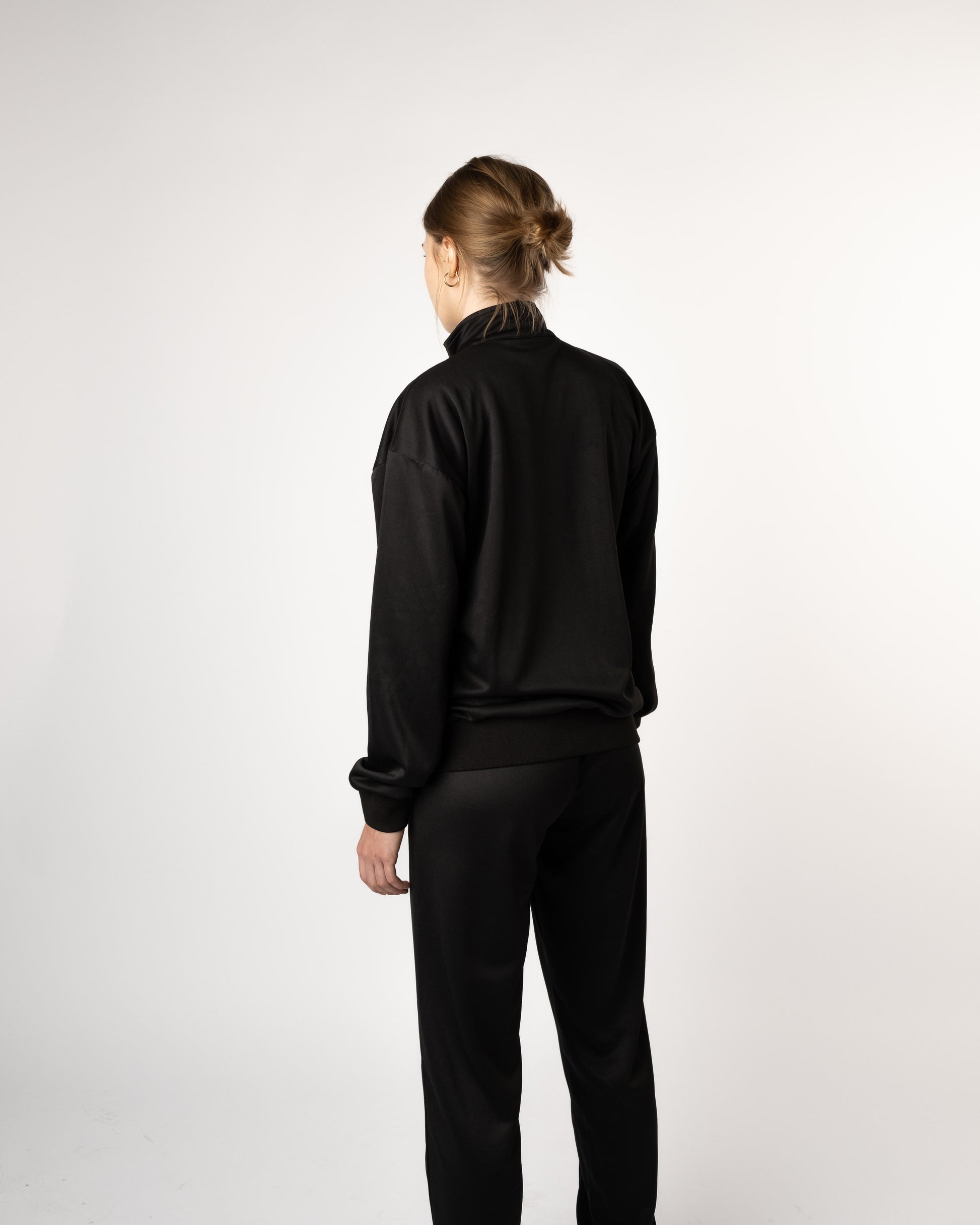 Achteraanzicht van model in GJA trainingspak, stoere en comfortabele trainingsbroek voor jonge dames - Gym Junkie Sportswinkel