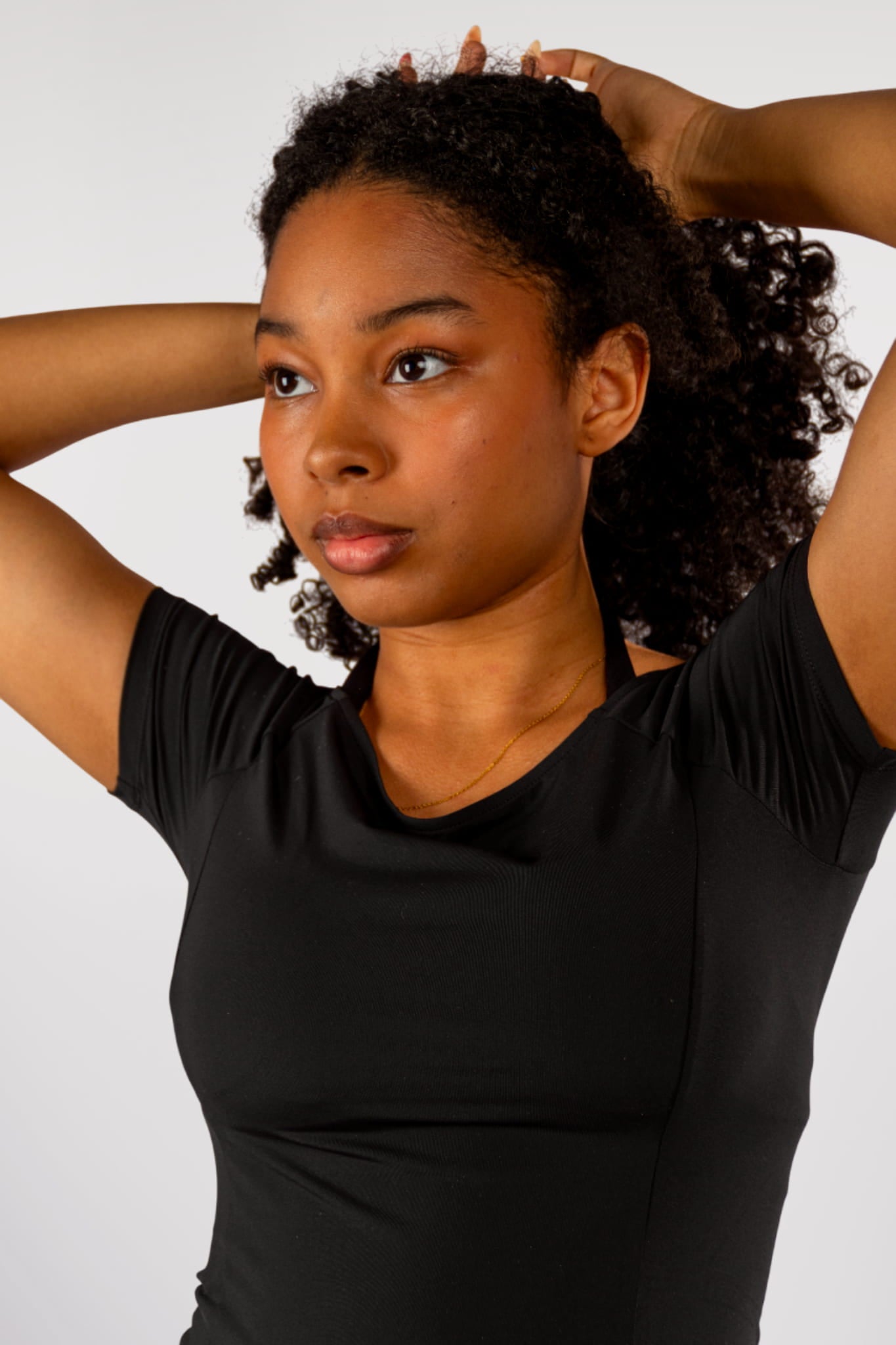 Dame houdt haar haar omhoog – close-up van de zwarte Nora boat neck T-shirt en Liberty halter bh