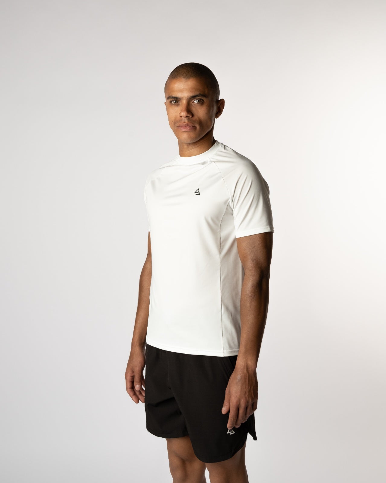 Mannelijke model in de witte Magna Trainings T-shirt in een licht zijwaartse pose, sportief en zelfverzekerd