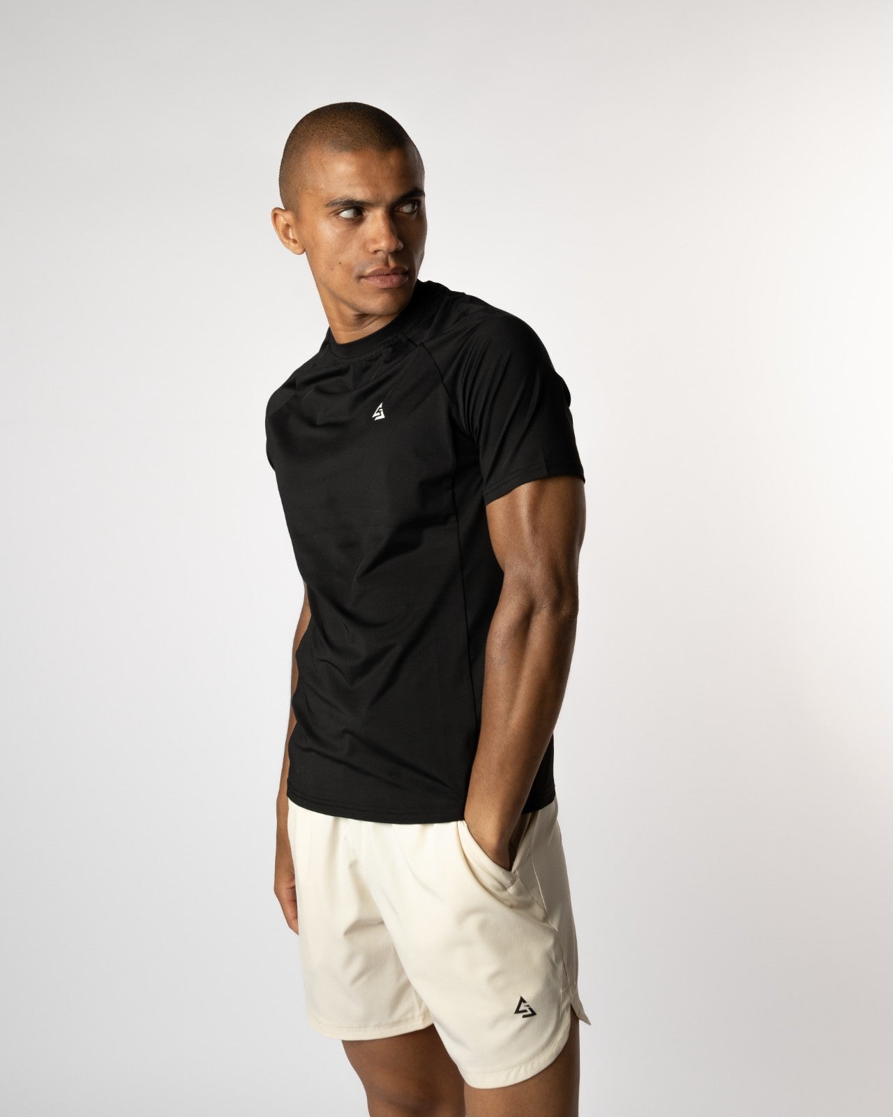 Zijaanzicht van mannelijke model in de Manga T-shirt en shorts, met hand in zak en gespannen houding — functionele gymwear voor atleten die geen ruimte laten voor excuseset met hand nonchalant in de zak — street-ready gymwear voor jonge sporters met attitude - Gymkleding voor mannen