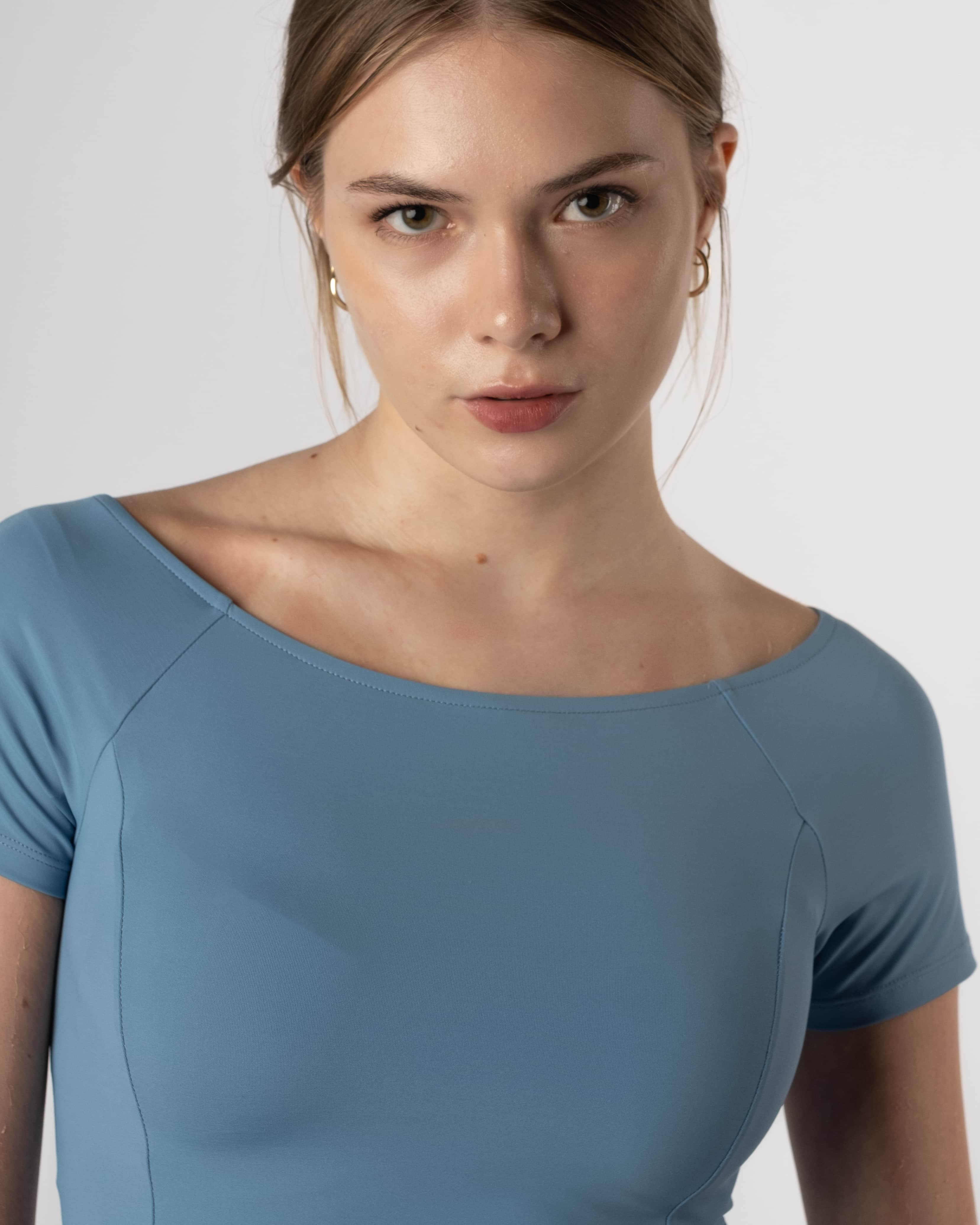 Detailfoto van de halslijn van de lichtblauwe Nora Boothals Crop Top van Gym Junkie.