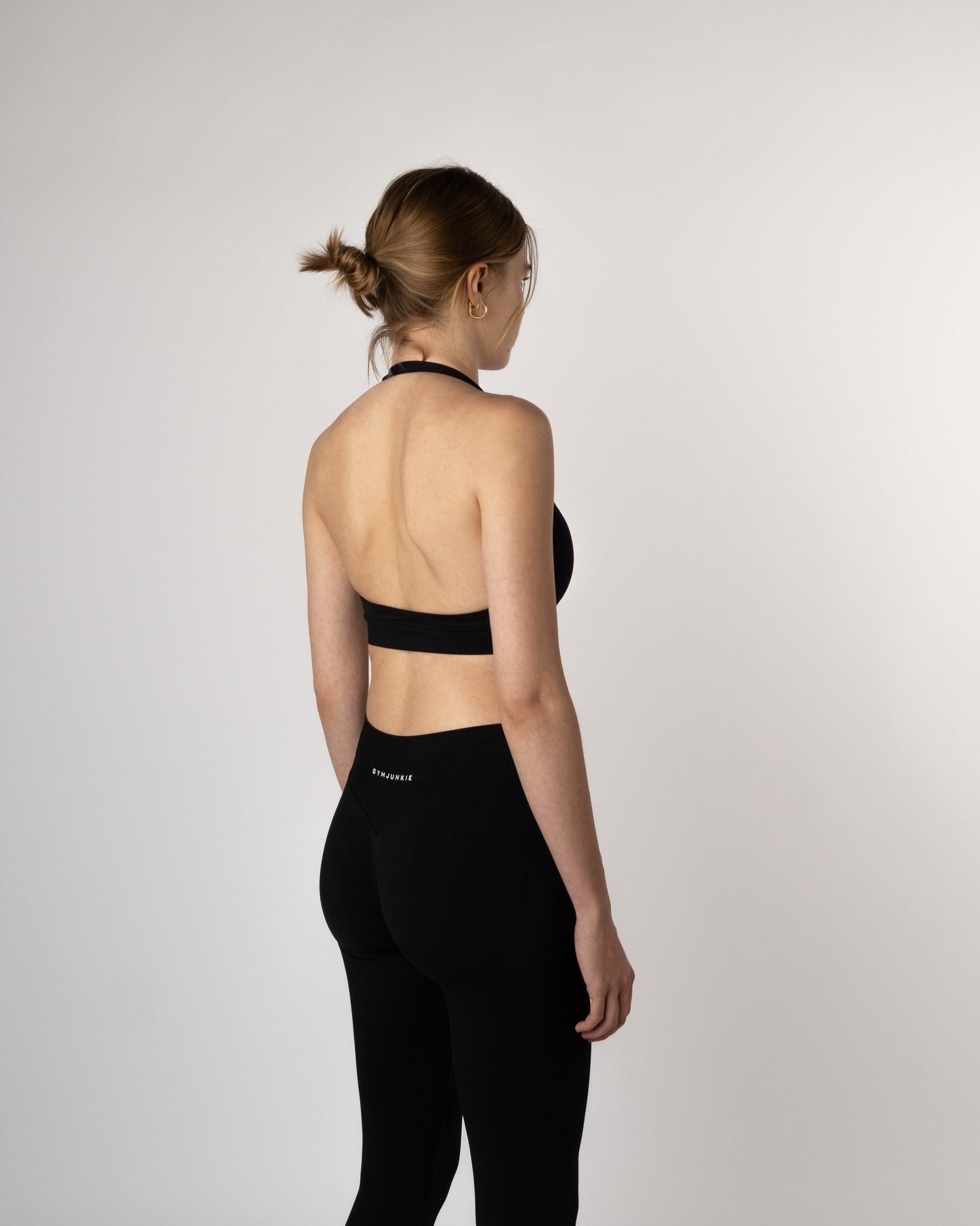 Achteraanzicht van model in zwarte Liberty naadloze sport-bh en legging, functionele en gedurfde gymkleding voor jonge vrouwen die kracht uitstralen in Nederland - Gym Junkie Dames sportset 